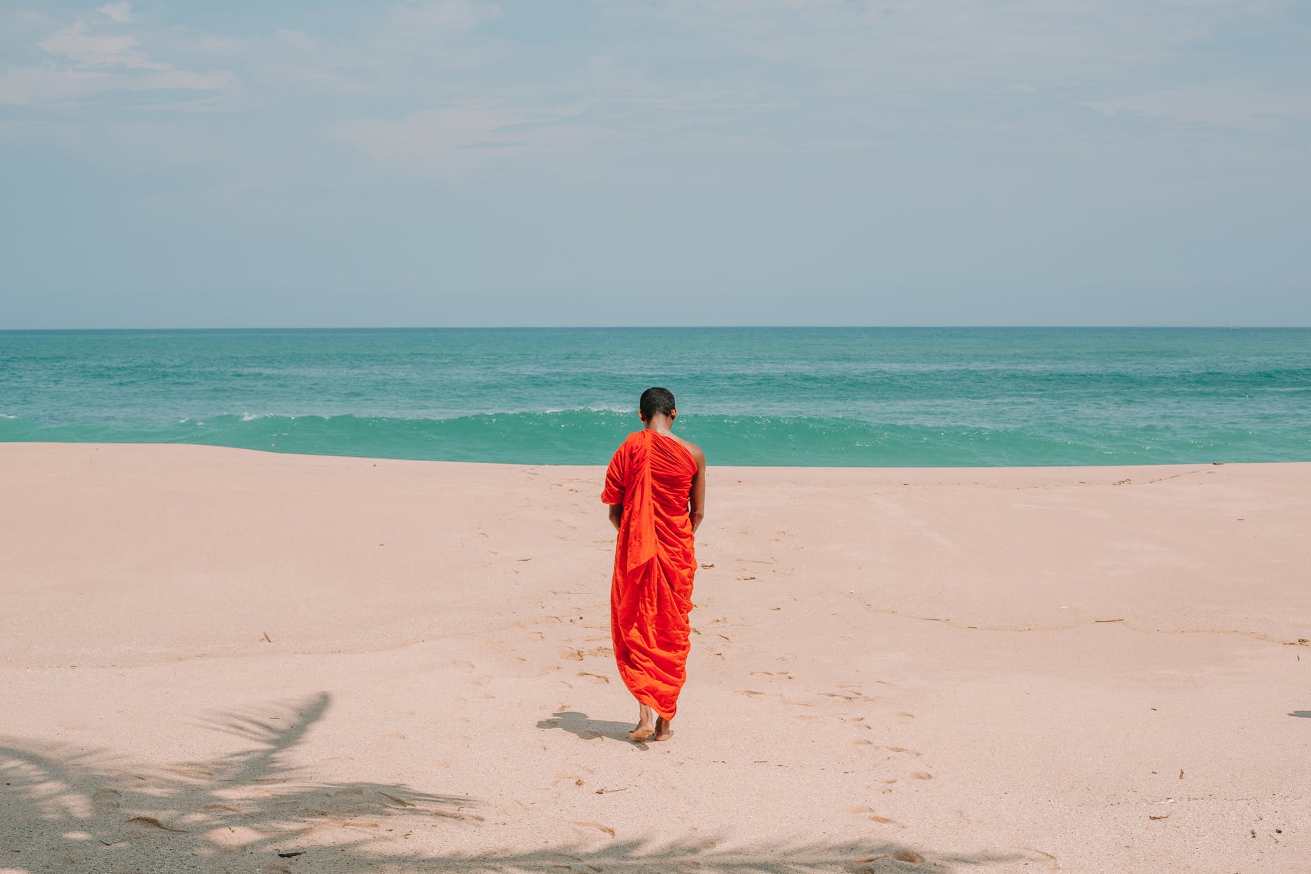 anonymous ethnic man strolling on ocean beach