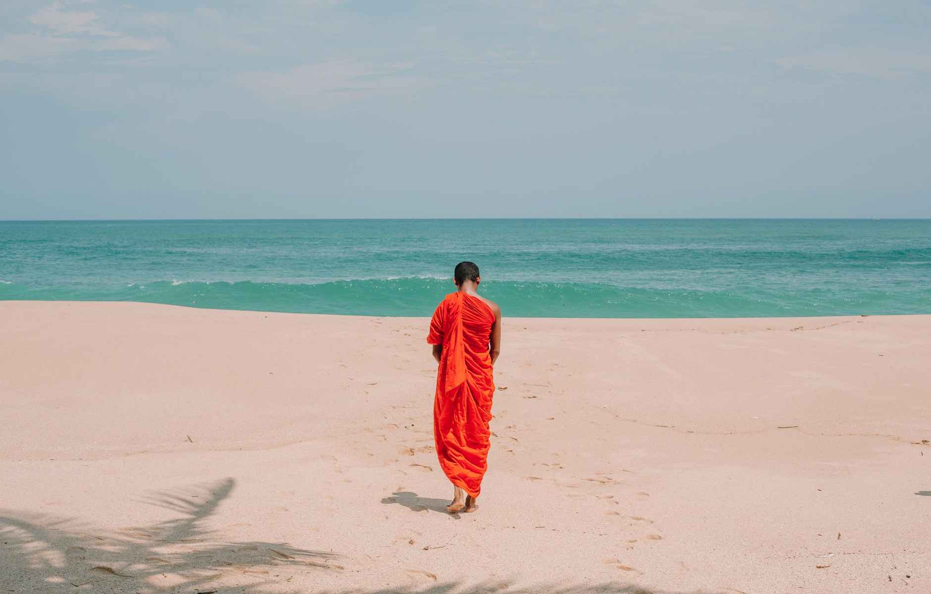 anonymous ethnic man strolling on ocean beach