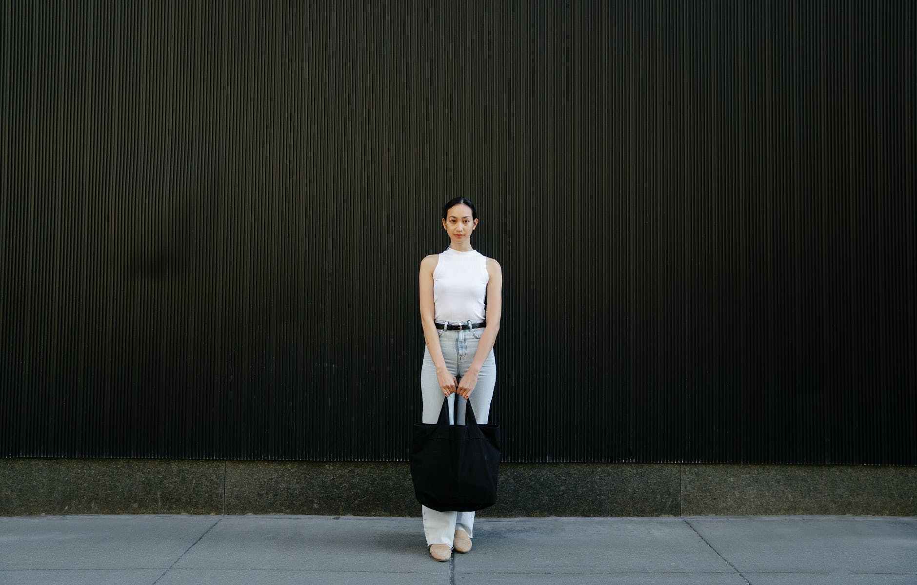 fashionable young ethnic female millennial standing on street and looking at camera